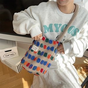 Detailed texture of plush bucket bag with colorful 3D dots and brand logo tag