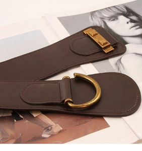 Detail of dark brown leather wide belt with vintage brass D-ring buckle on magazine