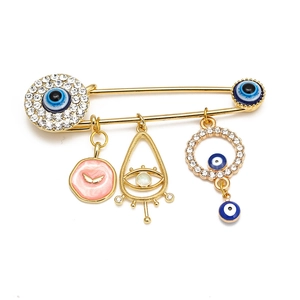 Detailed close-up of golden brooch pin featuring blue evil eye and crystal charms