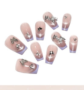 Macro detail of French purple cat eye fake nails with 3D silver butterflies and rhinestones