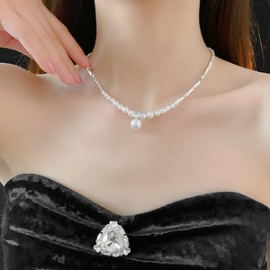 Close-up of elegant zircon pearl necklace worn by a model on a minimalist black background