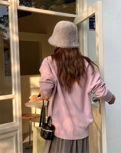 Chic lifestyle view of a woman wearing a soft grey faux fur bucket hat and pink knit sweater