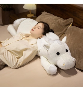 Macro detail of soft white plush pegasus horse with wings in a cozy bedroom setting