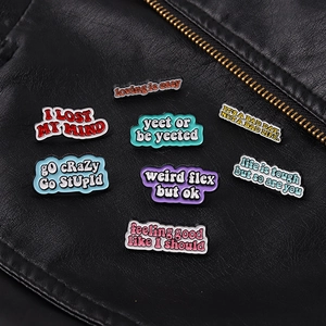 Detailed view of eight colorful enamel quote pins styled on a black leather jacket texture