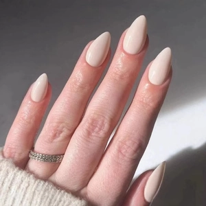 Faux ongles amande nude brillants et bague en argent sur un fond neutre élégant