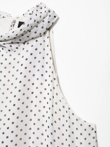 Close-up of white polka dot dress neckline showing pleated fabric detail and light texture