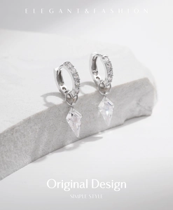 Detail of S925 sterling silver hoop earrings with a sparkling kite-shaped zircon pendant