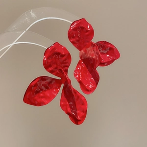 Close-up of red painted flower earrings with metallic luster and artistic petal details