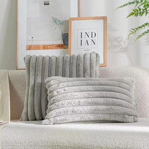 Close-up of gray striped faux rabbit fur pillows on a soft beige textured sofa