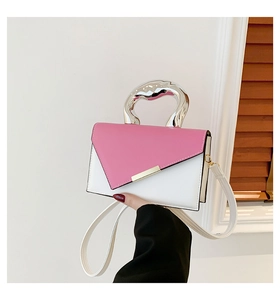 Detail of a pink and white color-block handbag with a unique silver fluid metal handle