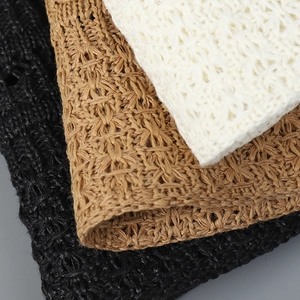 Detailed macro view of woven straw bucket hats in cream, tan, and black textured fabric