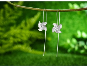 Macro shot of S925 sterling silver windmill earrings with matte finish on plant branch