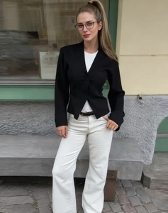 Primo piano di un blazer corto nero slim fit con due bottoni e un elegante rever a lancia