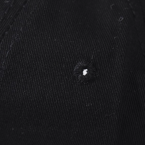 Macro detail of embroidered eyelet and washed black twill fabric on the baseball cap