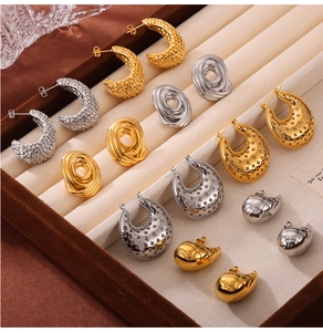 Detail of gold and silver earrings with textured patterns in a jewelry storage box
