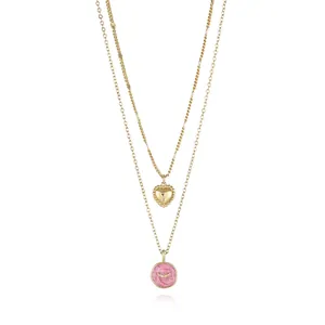 Detail view of double-layered 18K gold-plated necklace with pink enamel heart and moon pendant