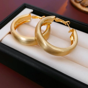Dettaglio macro di orecchini a cerchio spessi in oro satinato in una scatola per gioielli