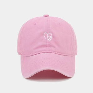 Gros plan détaillé sur la broderie cœur blanc d'une casquette en coton rose délavé