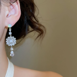 Nahaufnahme eleganter silberner Quastenohrringe mit Blumenmotiv und Zirkonia am Modell