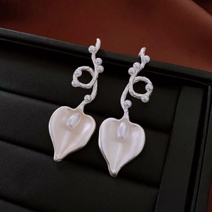 Detailed close-up of silver-toned vintage heart-shaped pearl drop earrings on display