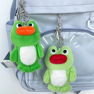 Detail of plush frog keychains with colorful lips hanging on a light blue backpack