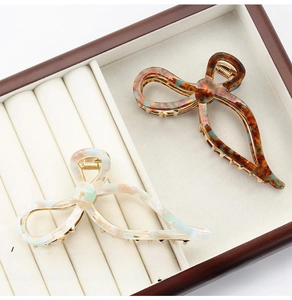 Macro detail of elegant acetate bow hair claws in tortoiseshell and pearly white finishes