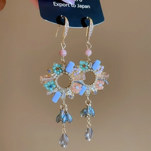 Detail of floral zircon tassel earrings featuring colorful crystals and golden base