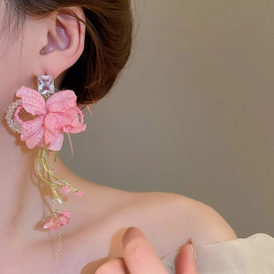 Detail of pink fabric flower earring with sparkling rhinestone and beaded green tassels