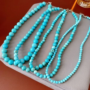 Close-up of four turquoise beaded necklaces with varied bead sizes on a display pad
