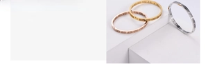 Detailed macro of stainless steel bangle featuring hollow Greek fret pattern and gold plating