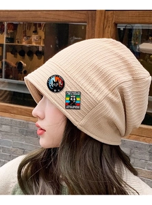 Detail of cartoon enamel cat pins on a beige beanie featuring funny nursing quotes