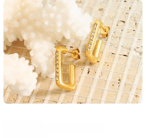 Détail de boucles d'oreilles rectangles dorées avec zircon et finition polie