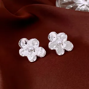 Elegant silver irregular flower stud earrings with white pearl on red silk fabric