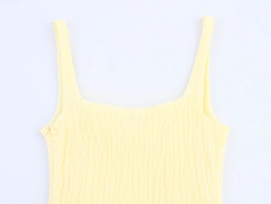 Detail showing smocked textured fabric and invisible zipper on light yellow dress