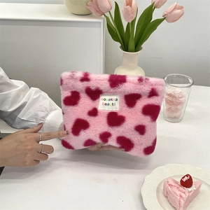 Detail of pink plush cosmetic bag with red hearts and floral aesthetic decor