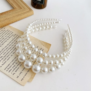Three sizes of elegant pearl headbands for weddings displayed on a vintage book page