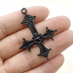 Gothic black metal inverted cross pendant with pentagram detail held for size scaling
