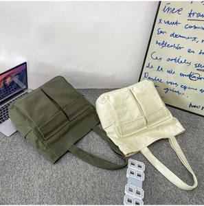 Detail view of large canvas tote bags in olive green and cream white with four front pockets