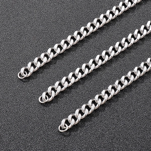 Detailed close-up of three polished silver stainless steel Cuban link chains on black