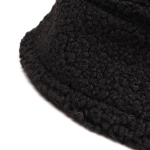 Close-up of black fuzzy faux shearling fabric texture on a stylish bucket hat brim