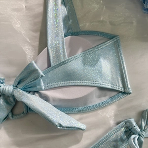 Macro detail of light blue glitter bikini top with holographic shimmer and side tie straps