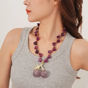 Detail of purple cherry acrylic pendant necklace with stones worn by a model