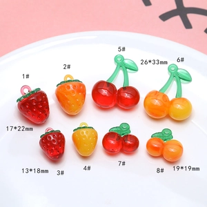 Flat lay of resin strawberry and cherry charms in various sizes on a white plate
