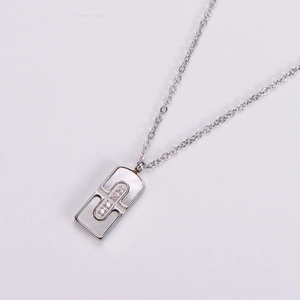 Macro shot of silver square pendant with white shell inlay and zircon details