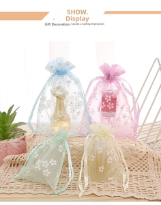 Detail of colorful organza drawstring gift bags with white floral prints on lace surface