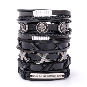 Detail of stacked black leather punk bracelets featuring metal skull and engraved quote plaque