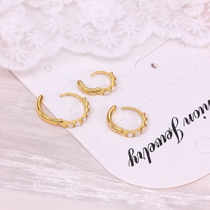 Detailed view of three gold hoop earrings with white opal stones on white jewelry card