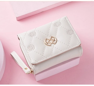 Detail view of cream trifold wallet with quilted embroidery and gold metal logo