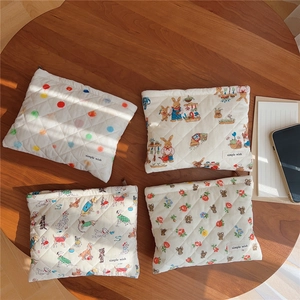 Quilted makeup bags with animal prints and patterns on a wooden desk with sunlight