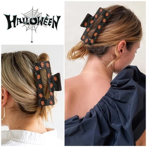Macro detail of Halloween large square hair claw clip with orange pumpkin motifs on hair